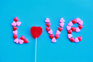 心形糖果拼出「love」，中間有紅色心形棒棒糖。