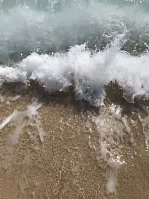 海浪衝擊濕潤的沙灘，帶有白色浪花和閃閃發光的水滴。