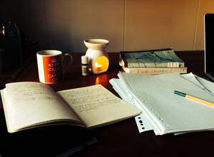 舒適的學習書桌，有打開的筆記本、杯子和溫暖發光的擴散器。
