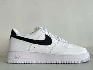 灰色表面上帶有黑色Swoosh的白色Nike Air Force 1運動鞋。