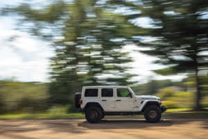 白色Jeep Rubicon在森林地區的泥路上行駛。