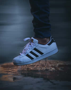 一對白色 adidas superstar 運動鞋在夜間水中濺水。 — Adidas GIF 壁紙