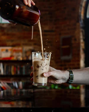 在磚牆酒吧，手將咖啡倒在冰上倒入玻璃杯。 — 4:5 壁紙