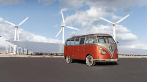 復古紅色和米色VW巴士停在太陽能板和風力發電機附近。