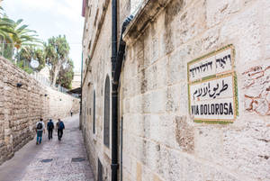 耶路撒冷一條狹窄的石巷，帶有苦路 Via Dolorosa 的多語標誌。