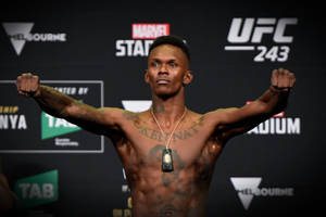 一位有紋身的赤裸上身男拳手在 UFC 稱重中舉起拳頭。