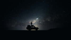 星空下車輛上的人影剪影與銀河