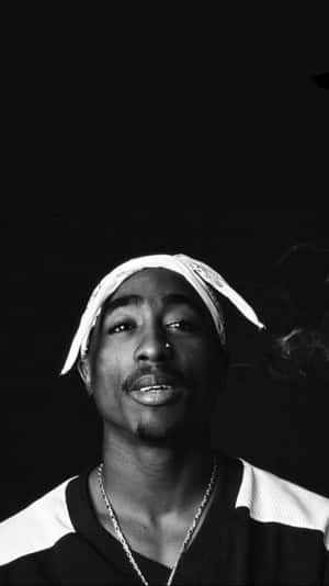 Tupac Shakur 在黑白照片中微笑抽煙。