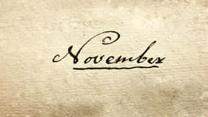 在紋理米色紙上以黑色墨水手寫的「November」一詞。