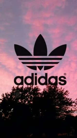 Adidas標誌映襯著粉紅和紫色日落天空與深色樹木。