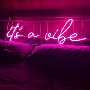 昏暗房間的床上方，一個寫著 it's a vibe 的粉紅色霓虹燈牌。