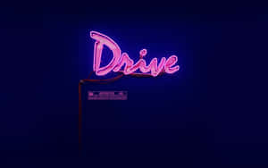 粉紅色霓虹燈牌，上面寫著「Drive」，並帶有限制標籤，背景為深藍色。