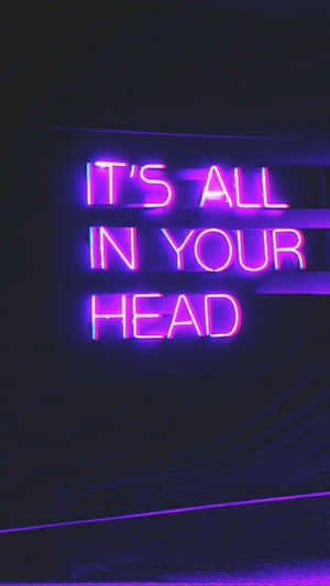 深色牆上寫著「IT'S ALL IN YOUR HEAD」的紫色霓虹燈牌。
