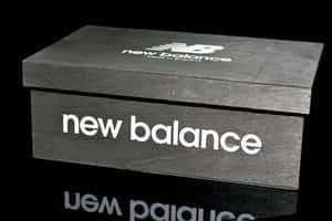 黑色New Balance鞋盒，帶有白色標誌，置於反射表面。