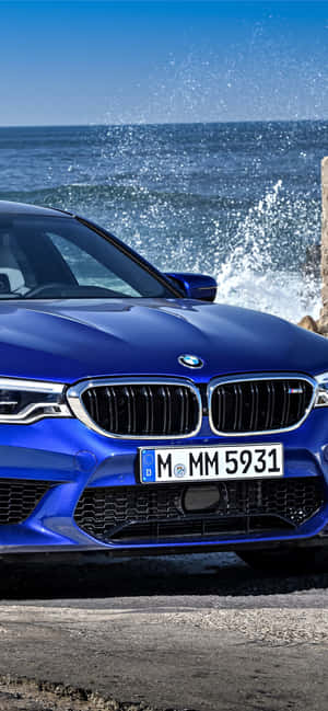 藍色BMW M5停泊在海洋旁邊，附近有浪花拍岸。