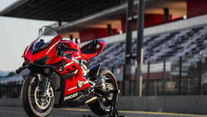 紅色Ducati電單車在賽道上，背景是空看台。