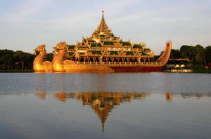 金色寺廟船在水上漂浮，夕陽下倒影。 — 香港 壁紙
