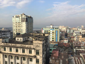 多雲天空下，新舊建築密集的城市景觀。 — 黃昏 壁紙