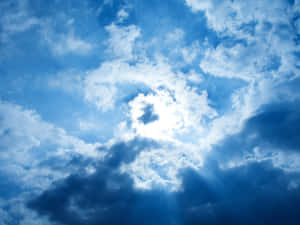 陽光透過戲劇性的藍白雲層照射出來。 — 雲朵 壁紙