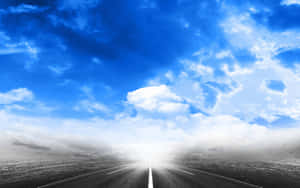 一條道路在戲劇性的藍天白雲下消失在明亮的光線中。