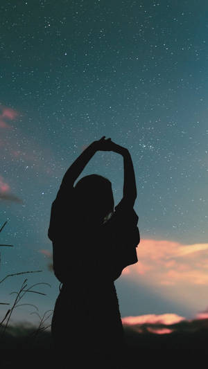 一個人在暮色中於星空下伸展雙臂 — 星空夜 壁紙