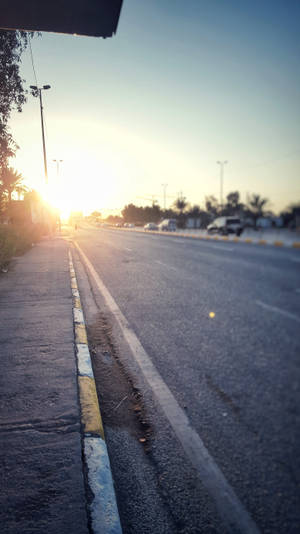 夕陽下的寧靜城市道路，汽車駛向遠方。 — 日落大道 壁紙