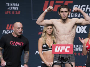 UFC拳手在稱重活動中與官員和橫幅一起屈曲手臂。