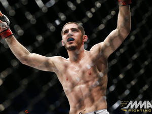 MMA拳手在八角籠內高舉雙臂慶祝勝利。