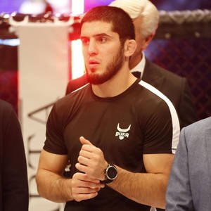 身穿帶白色條紋黑色襯衫的 MMA 拳手在八角籠內握緊拳頭站立。