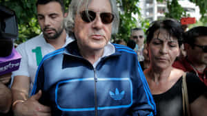 穿著藍色Adidas夾克和太陽眼鏡的男性被記者和人們包圍。 — 網球 壁紙