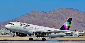 Volaris 飛機在跑道上，背景有山脈