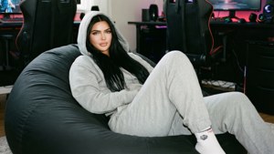 穿著灰色連帽衫的女性在遊戲室中的黑色豆袋椅上放鬆，配有RGB燈光。 — Kylie Jenner 壁紙