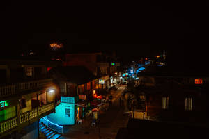 夜晚街道場景，發光的霓虹燈招牌和棕櫚樹映襯著黑暗的天空。 — 螢幕保護 壁紙