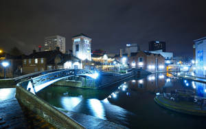 運河上亮燈橋樑的夜景，背景是城市建築。 — 夜景城市 壁紙