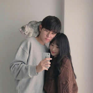 年輕情侶在室內與貓咪在男士肩膀上自拍。 — 情侶 壁紙