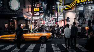 黃色復古汽車在霓虹燈下穿越夜晚東京繁忙的街道。