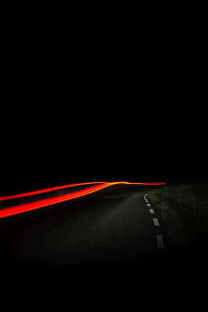 夜間黑暗蜿蜒道路上汽車的紅色光軌。