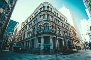 一座歷史悠久的石造建築，帶有拱形窗戶和陽台，位於城市街道上，有行人。 — 建築 壁紙