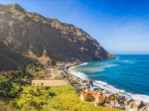 沿海村莊依偎在陡峭的山脈旁，伴隨著碧綠的海浪。
