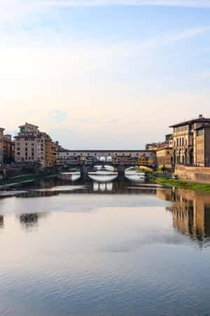 佛羅倫斯阿諾河上的 Ponte Vecchio 橋，日落時分建築物倒影。 — 晴朗天空 壁紙