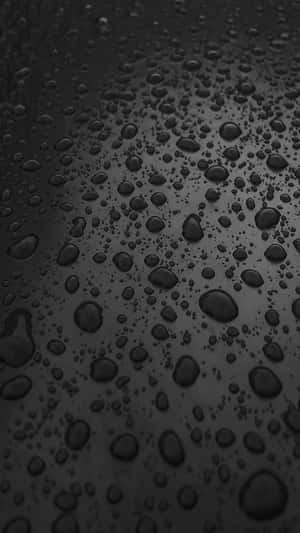 閃爍的雨滴在深色光滑表面上，柔和漸變燈光。