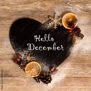 心形黑板，帶有Hello December文字和冬季裝飾，置於木頭上。