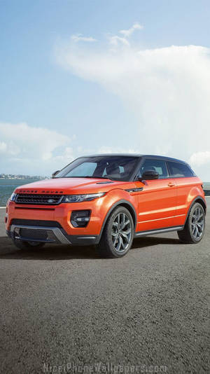橙色Range Rover Evoque停泊在瀝青路上，藍天白雲。