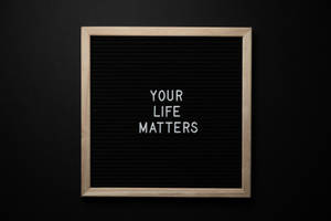 一個帶框的氈板，上面有白色字母的訊息「Your Life Matters」。