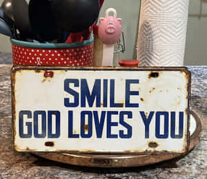 廚房檯面上寫有「Smile God Loves You」的質樸金屬標牌。