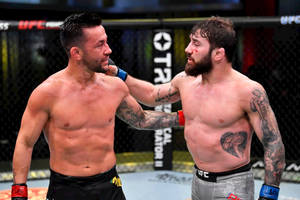 兩名男性MMA拳手在八角籠中，臉上帶血。