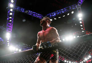 一名血跡斑斑的MMA選手在明亮的燈光下於八角籠內慶祝勝利。