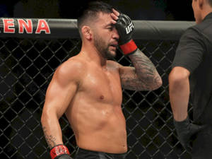 一個有紋身的男性MMA拳手在UFC八角籠內擦拭汗水。