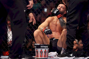 筋疲力竭的MMA拳手在八角籠內比賽後飲水。