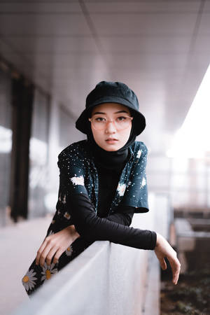 年輕女性戴黑色漁夫帽和花卉頭巾在室內倚靠欄杆